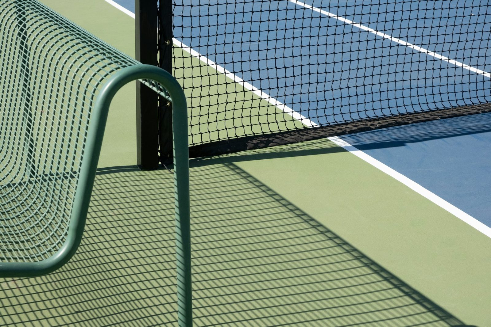 Net post on a blue and green hard tennis court